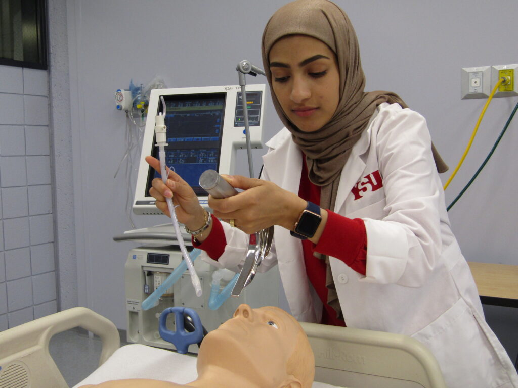 Respiratory Care student practicing patient care skills with high-fidelity adult mannequin